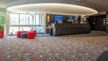 A reception area with a modern design, featuring a reception desk, seating area, and large windows providing natural light.