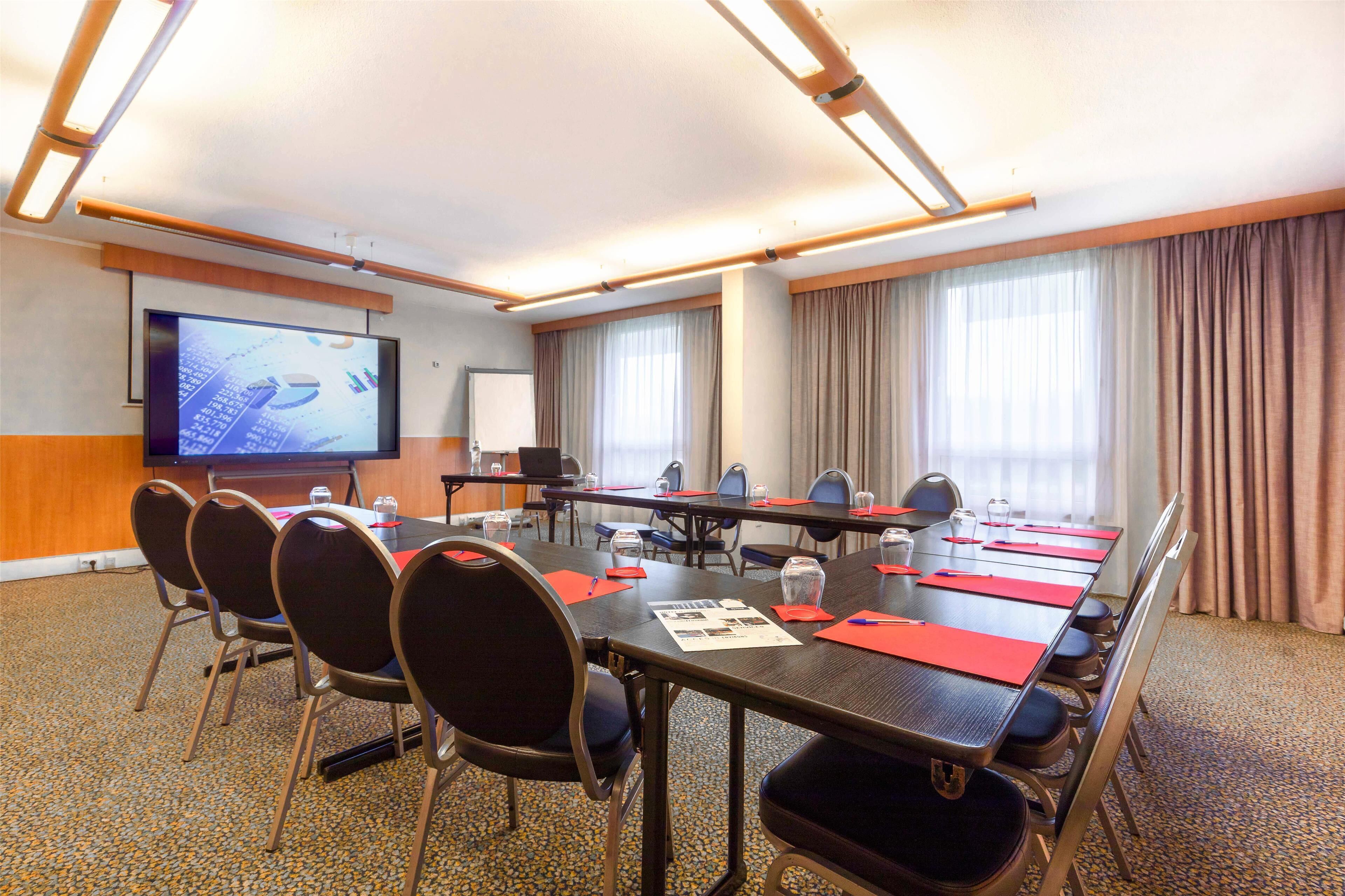 A conference room with a long table, chairs, a projector screen, and a whiteboard.