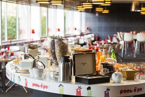 A breakfast buffet with various food items and beverages, including a coffee pot, a fruit bowl, and a juice dispenser. - KYRIAD MONTCHANIN - Le Creusot (Montchanin)