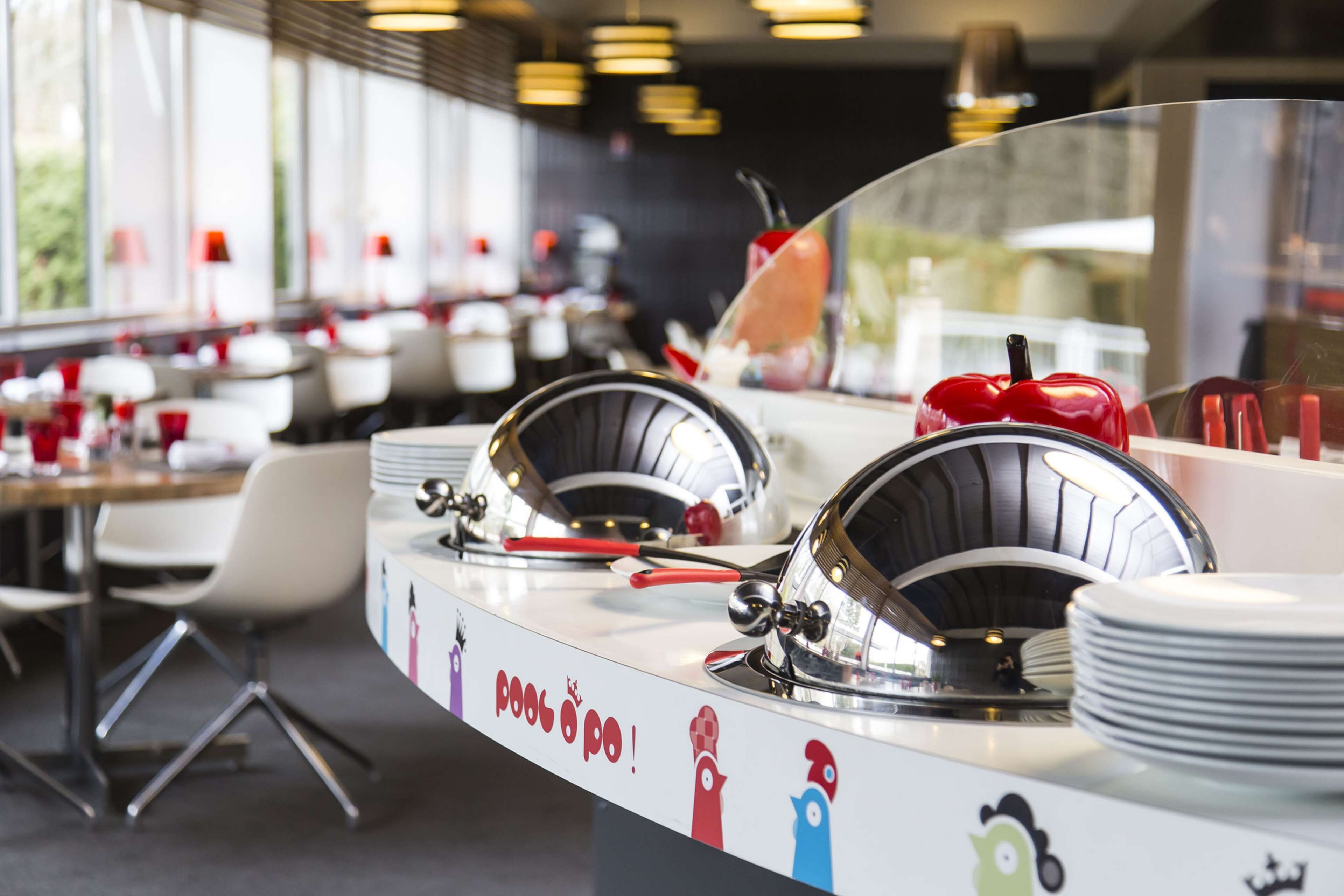 Un restaurante moderno con una barra curva, vajilla de metal y una decoración mural original.