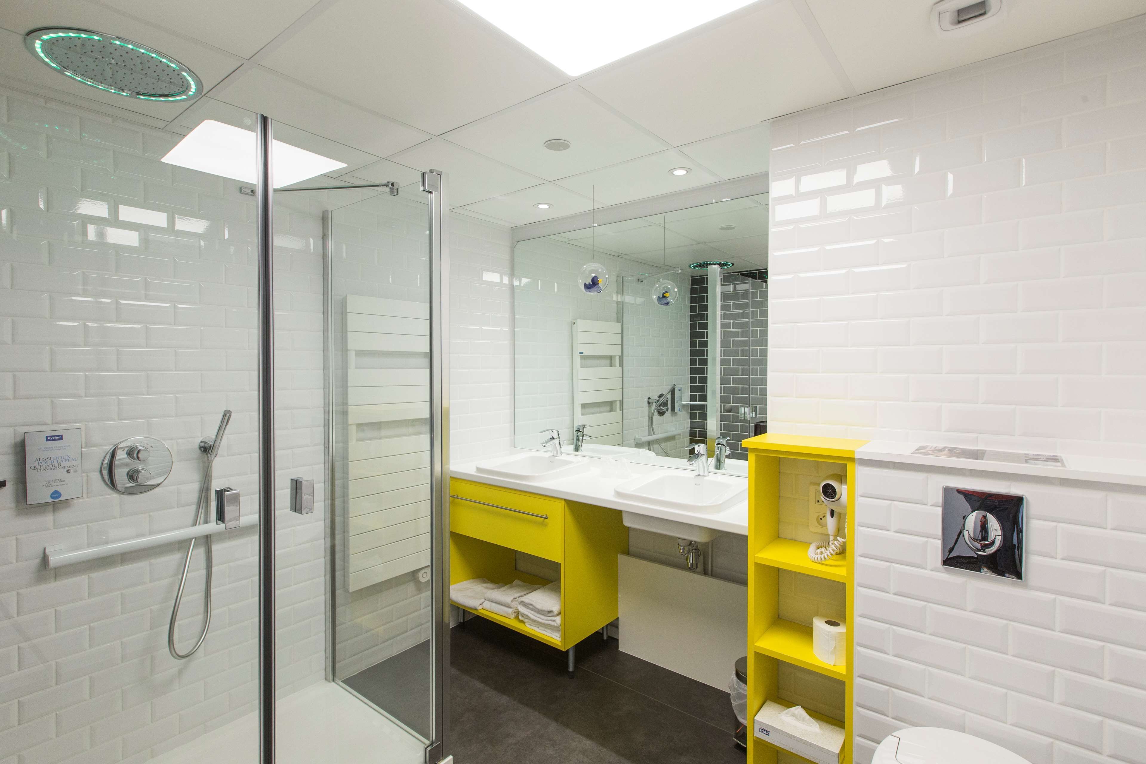 A modern bathroom with a glass-enclosed shower, dual sinks, and a yellow vanity.