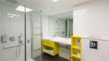 A modern bathroom with a glass-enclosed shower, dual sinks, and a yellow vanity.