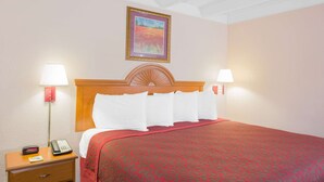 Habitació d'hotel amb un llit, dues làmpades de nit, una tauleta de nit amb un telèfon i un quadre encimbellat a la paret.