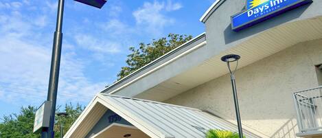 A Days Inn by Wyndham hotel with a clear sky, a signboard, and a well-maintained entrance area.