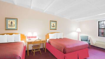 A hotel room with two beds, a desk, a chair, and two framed pictures on the wall.