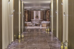 A luxurious hallway with marble flooring, elegant furniture, and decorative lighting fixtures.