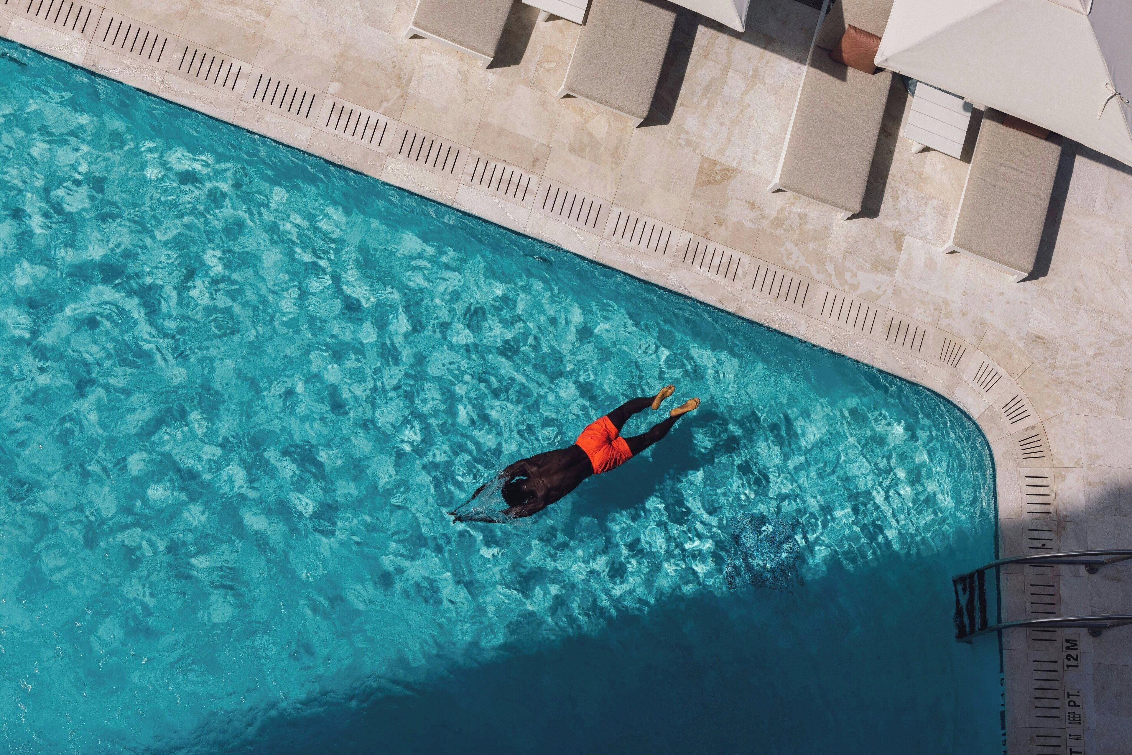 An aerial view of a swimming pool with a person swimming.