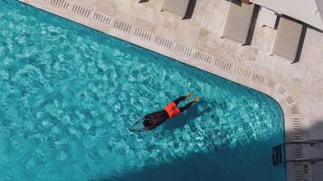 An aerial view of a swimming pool with a person swimming.