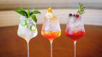 Tres cócteles en copas de martini, con hielo, adornos y un fondo desenfocado.