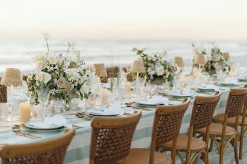 A person sitting on a beach with candles and a bowl, near the water. at The St. Regis Longboat Key Resort