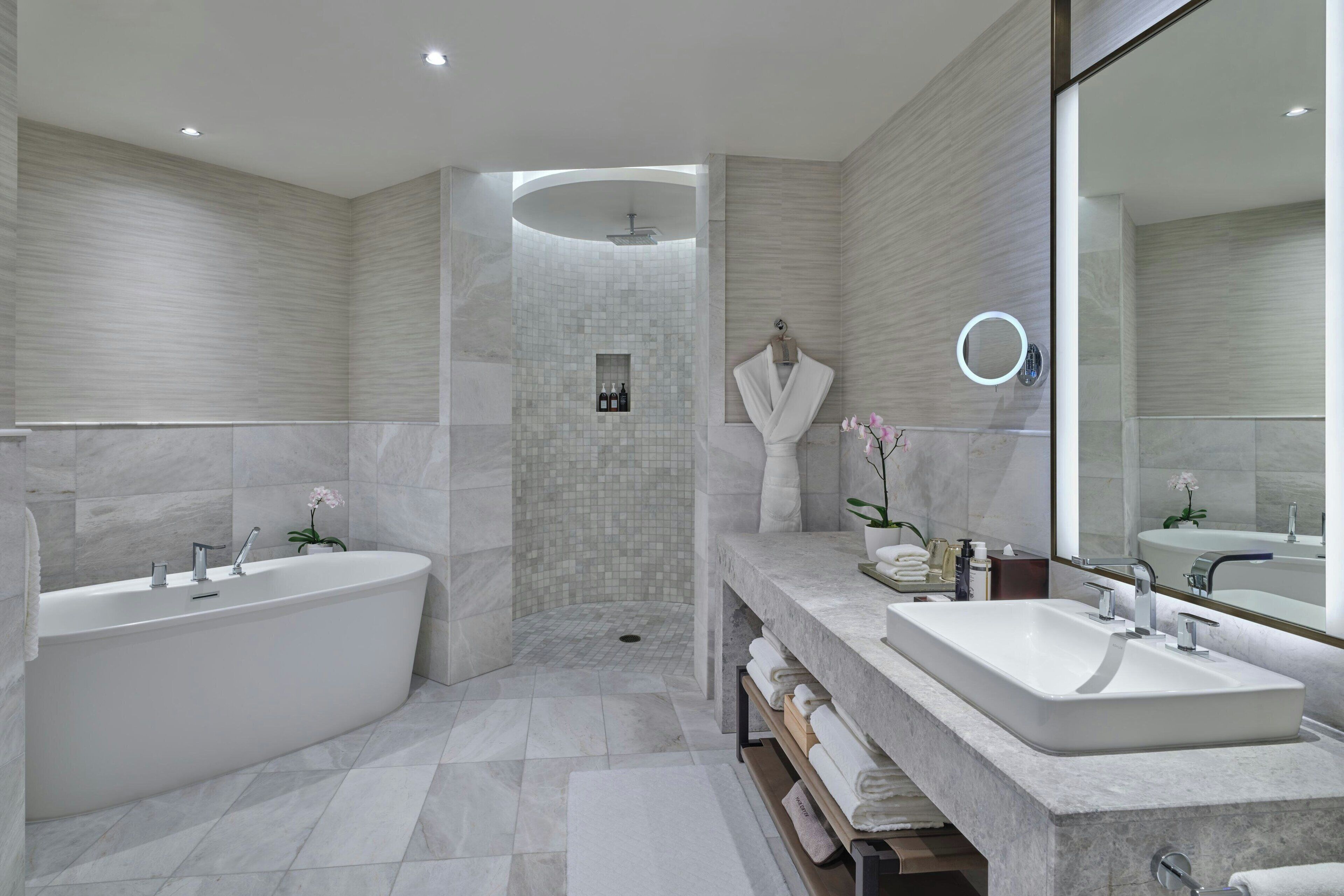 Un baño moderno con una bañera independiente, una ducha a ras de suelo y un tocador con un espejo grande.