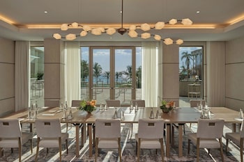 A modern bar area with a central island, bar stools, and a unique ceiling design. at The St. Regis Longboat Key Resort