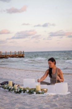 A modern hotel room with a large bed, a TV, a desk, and a view of the sea. at The St. Regis Longboat Key Resort