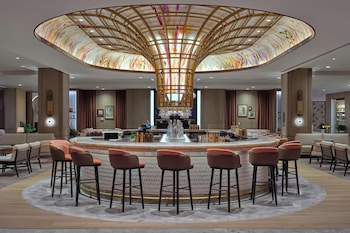 A modern hotel corridor with glass doors, a marble floor, and a ceiling with linear light fixtures. at The St. Regis Longboat Key Resort