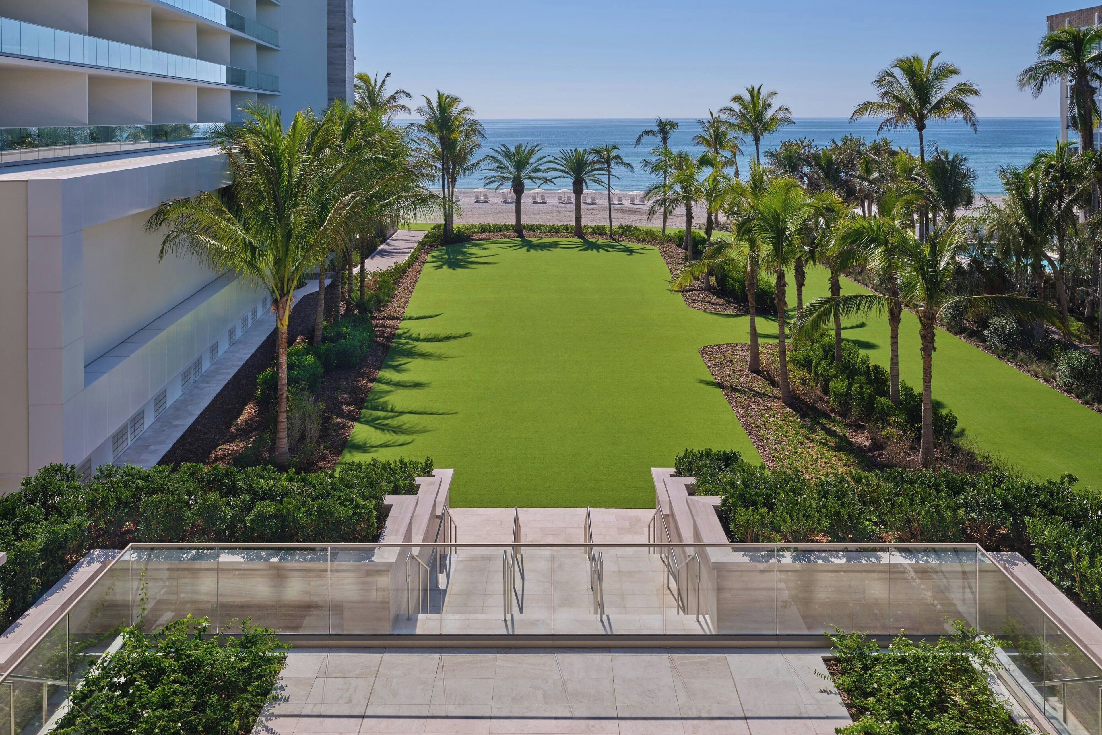 A golf course with a clear view of the ocean and palm trees.
