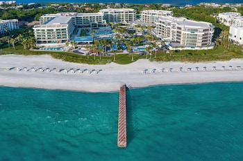 A modern dining area with a long table, chairs, and a view of the ocean. at The St. Regis Longboat Key Resort