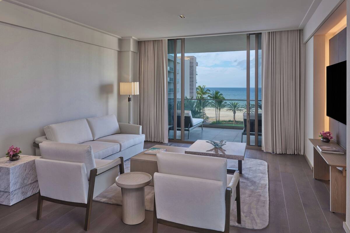Ein modernes Hotelzimmer mit Balkon, einer Couch, einem Couchtisch und einem Fernseher.