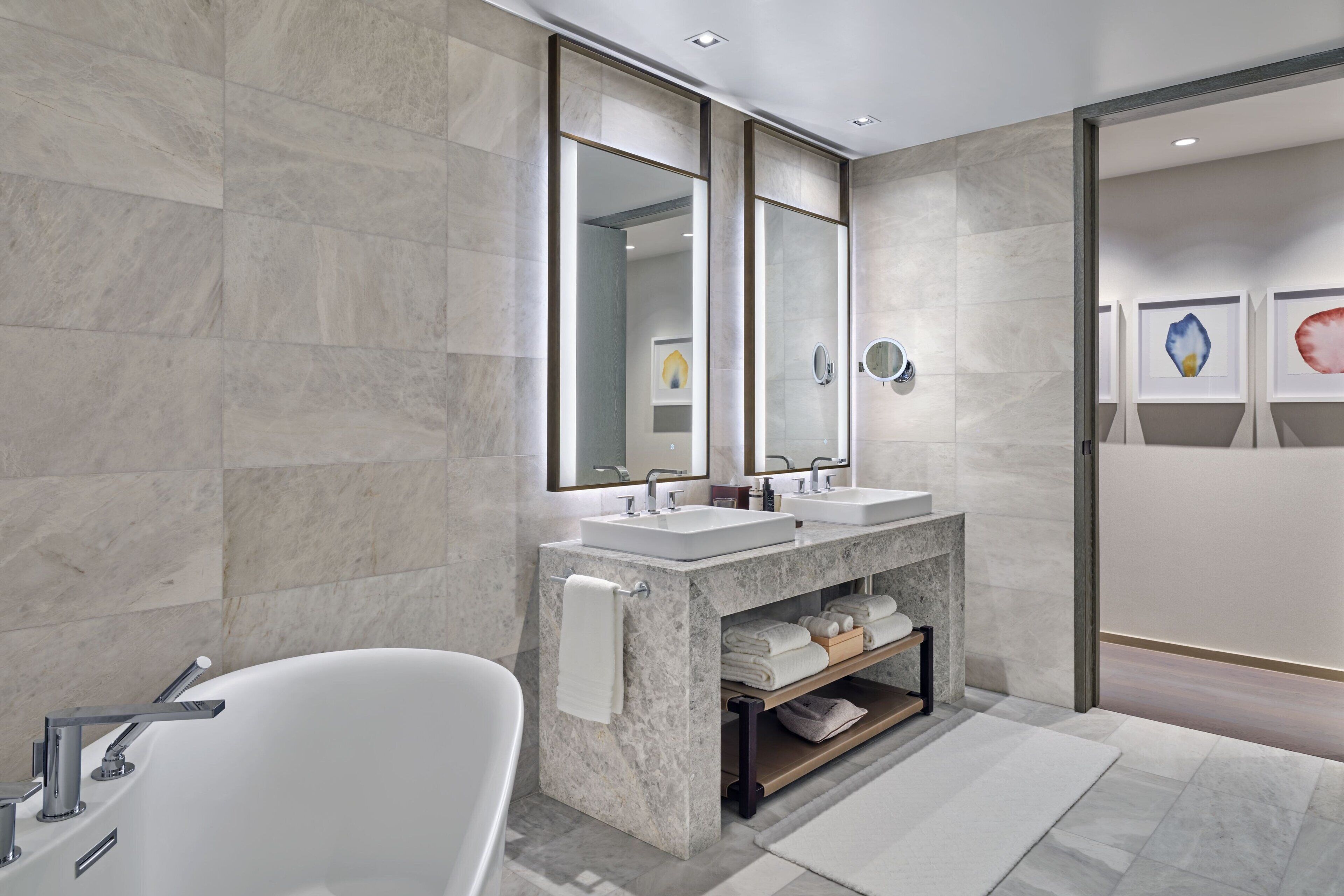 Une salle de bain moderne avec une baignoire sur pieds, deux lavabos et un meuble-lavabo avec un miroir.
