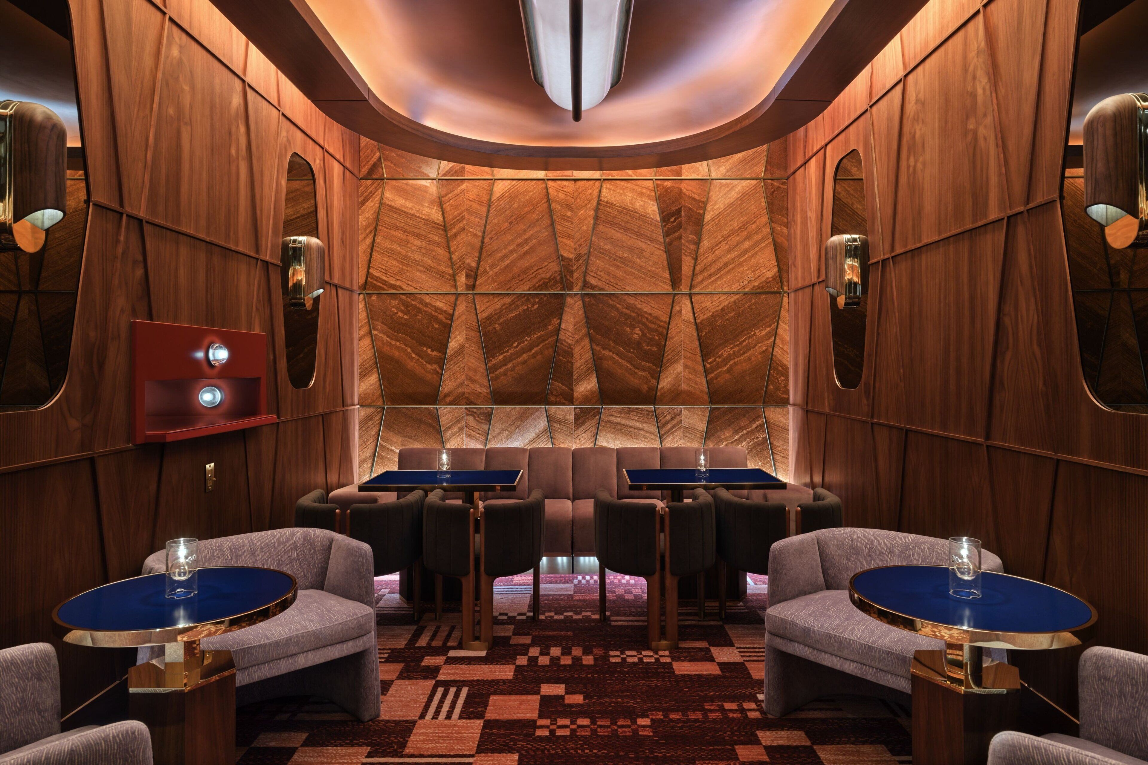 A luxurious interior with a geometric wood panel wall, a patterned carpet, and modern furniture.