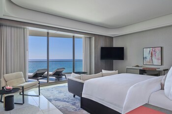 A conference room with a long table, chairs, and a large window with a view of palm trees and a pool. at The St. Regis Longboat Key Resort