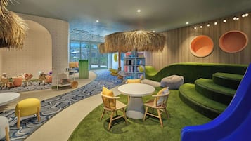 Children can play and learn in this vibrant play area with a round table, slide, and cozy seating.