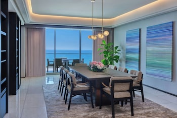 A balcony with wicker furniture, a table with a vase, and a view of the sunset over the ocean. at The St. Regis Longboat Key Resort