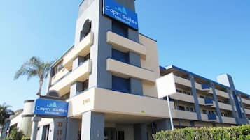Un hotel de varios pisos con un letrero azul llamativo que dice "Capri Suites ANAHEIM".