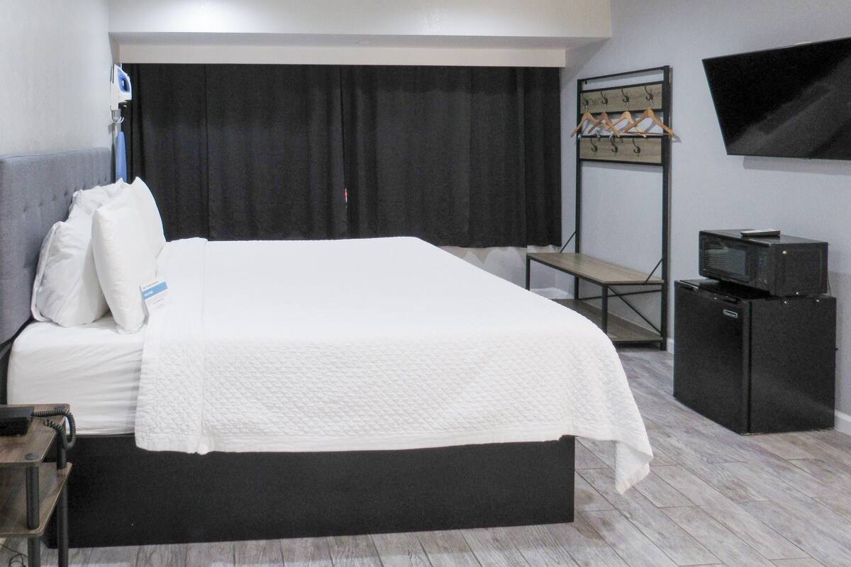A hotel room with a large bed, a desk, a television, and a minibar.