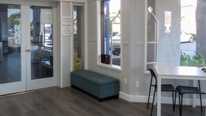 A room with a bench, a table, and chairs. There are signs on the door and windows. - Capri Suites Anaheim (Anaheim)