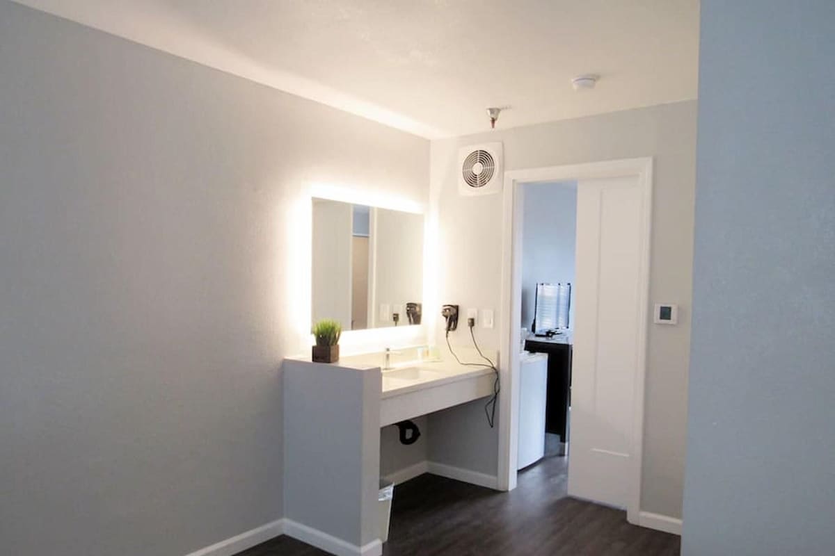A modern bathroom with a large mirror, a vanity, and a shower area.