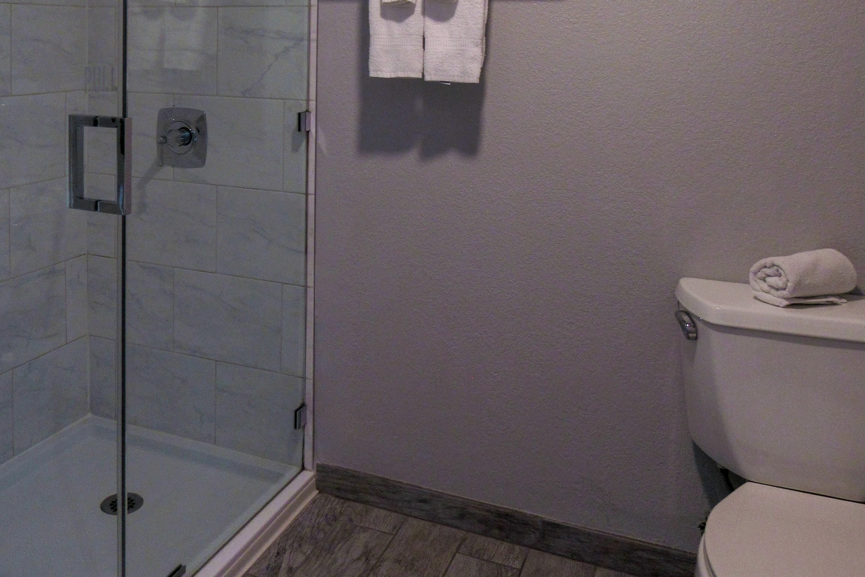Une salle de bain avec une douche à parois de verre, des toilettes et une serviette accrochée au mur.