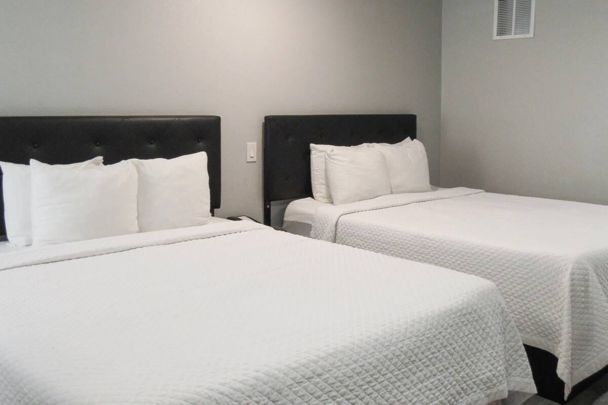 A hotel room with two single beds, each with a black headboard and white bedding.