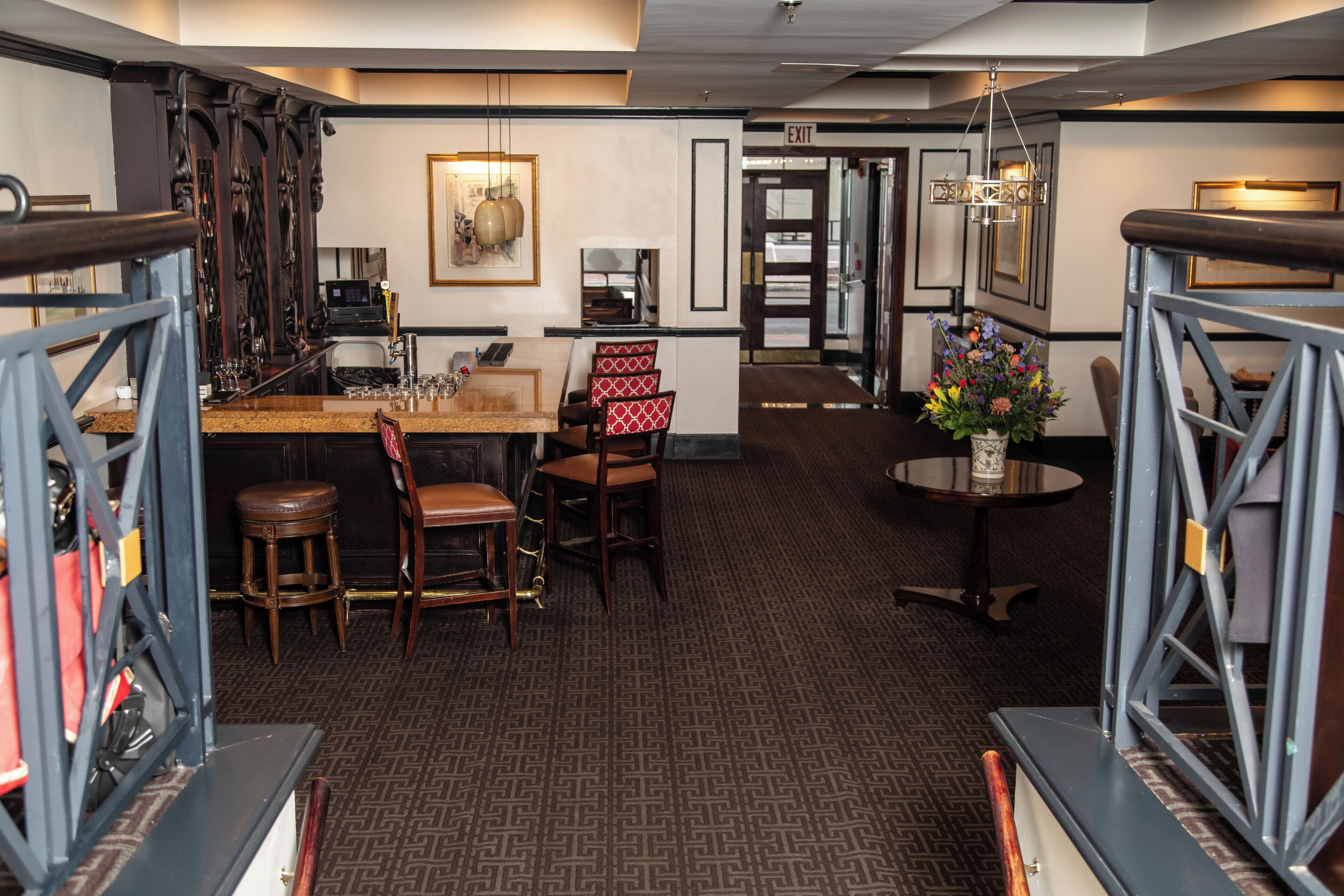 Una hall d'albergo con zona bar, posti a sedere e un vaso decorativo.