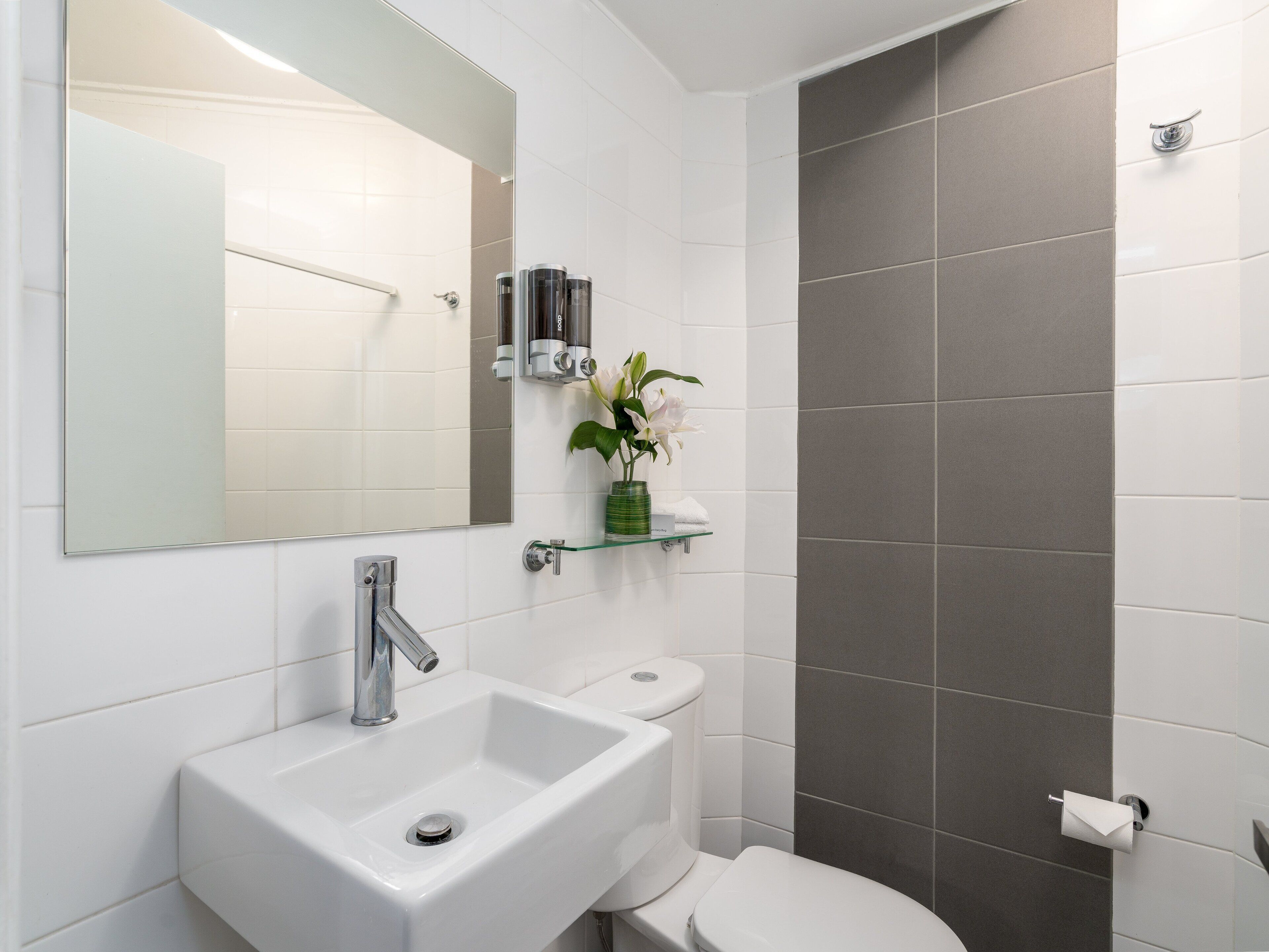 A bathroom with a white sink, a toilet, and a shower area.
