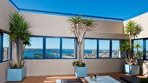 A modern rooftop terrace with large windows, a seating area, and potted plants. - Park Regis City Centre (Sydney)