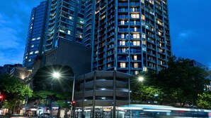 A high-rise building with multiple floors and balconies, surrounded by trees and streetlights. - Park Regis City Centre (Sydney)