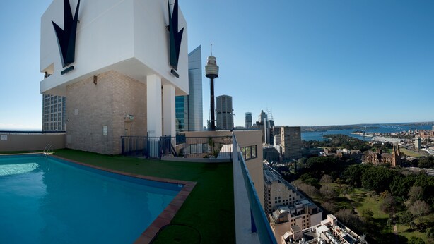 A rooftop pool with a clear view of a city skyline, including a prominent tower and a historic building. - Park Regis City Centre (Sydney)
