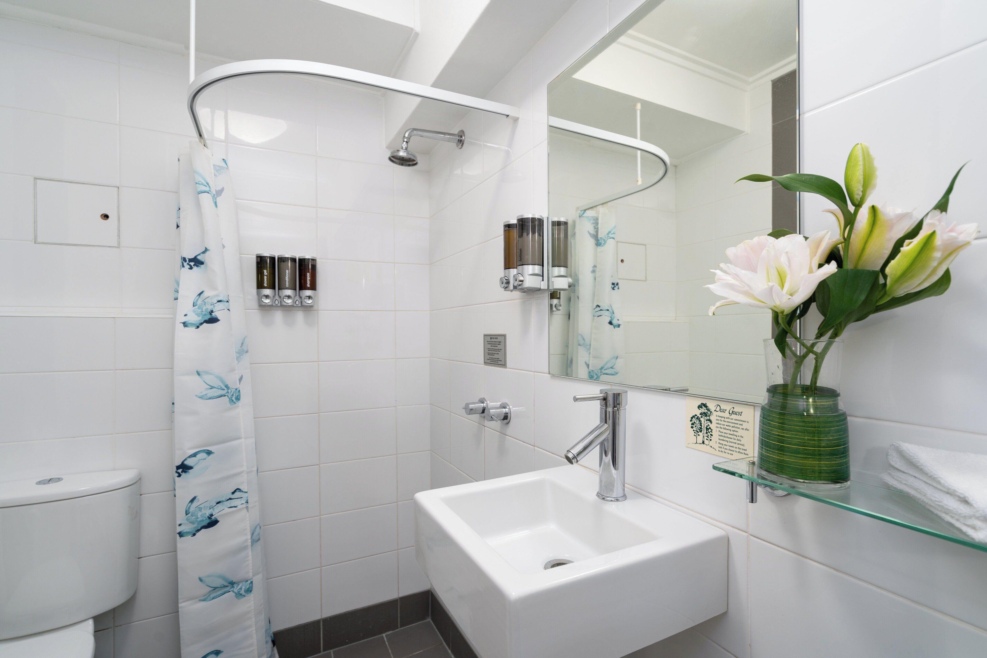Un baño moderno con cabina de ducha de vidrio, un lavamanos blanco y un espejo sobre él.