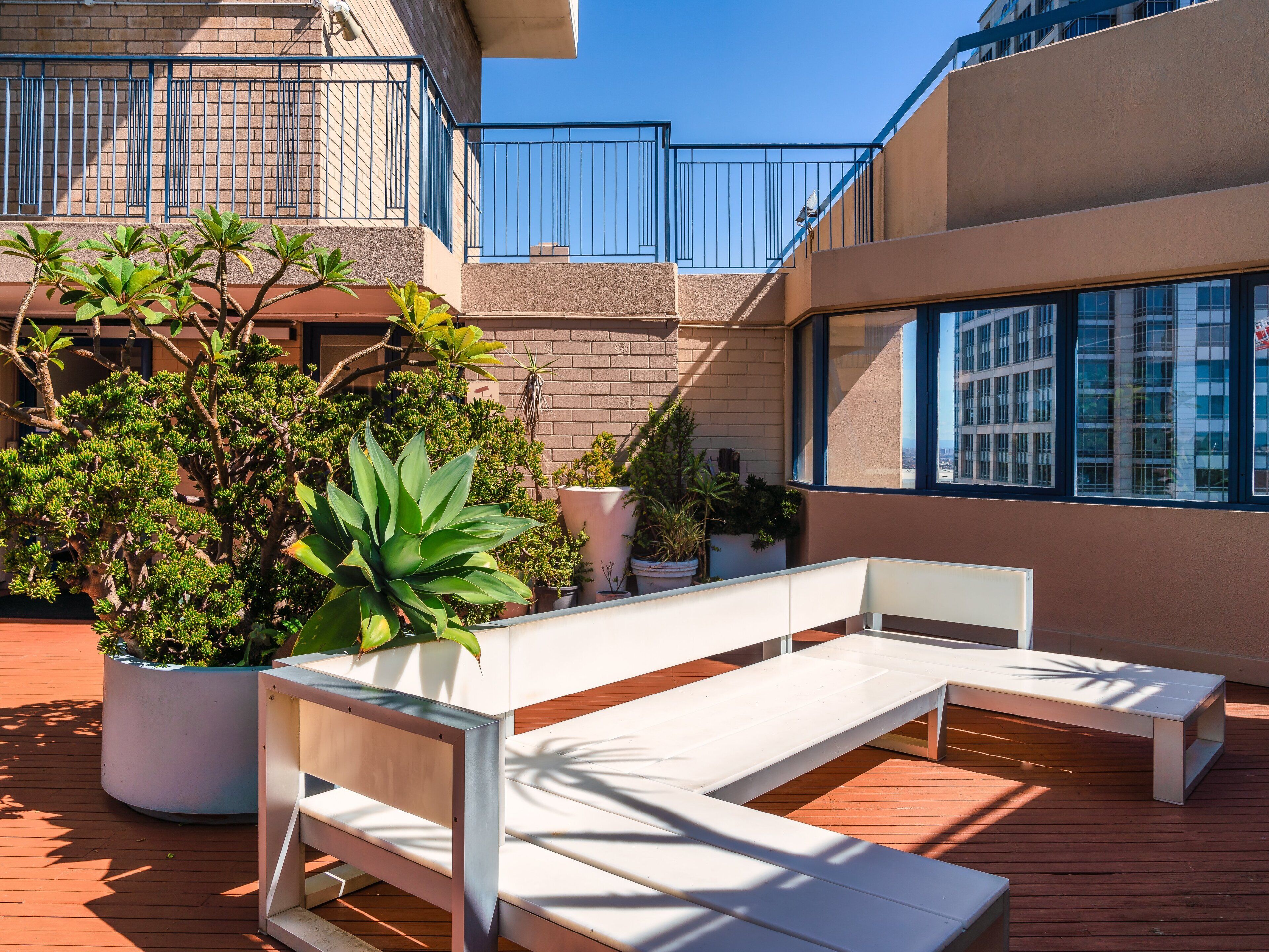 Una terraza en la azotea con zona de estar, plantas en macetas y vistas a un paisaje urbano.