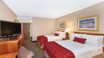 A hotel room with two beds, a TV, a desk, and a chair.
