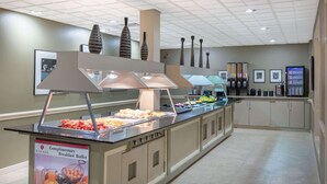Een ontbijtbuffet met diverse soorten eten, een bord met daarop de vermelding van het gratis ontbijt, en een automaat.