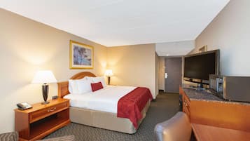 A hotel room with a bed, bedside lamps, a desk with a telephone, a television, and a microwave.