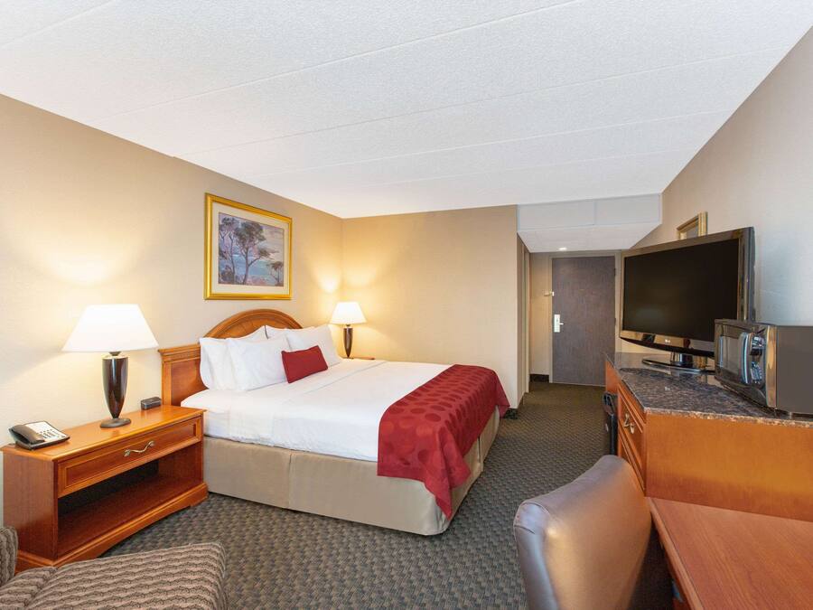 Een hotelkamer met een bed, bedlampen, een bureau met telefoon, een televisie en een magnetron.