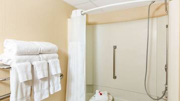 A bathroom with a shower, a towel rack with folded towels, and a shower curtain.