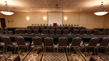Una sala conferenze con un lungo tavolo, file di sedie e uno schermo per proiezioni.