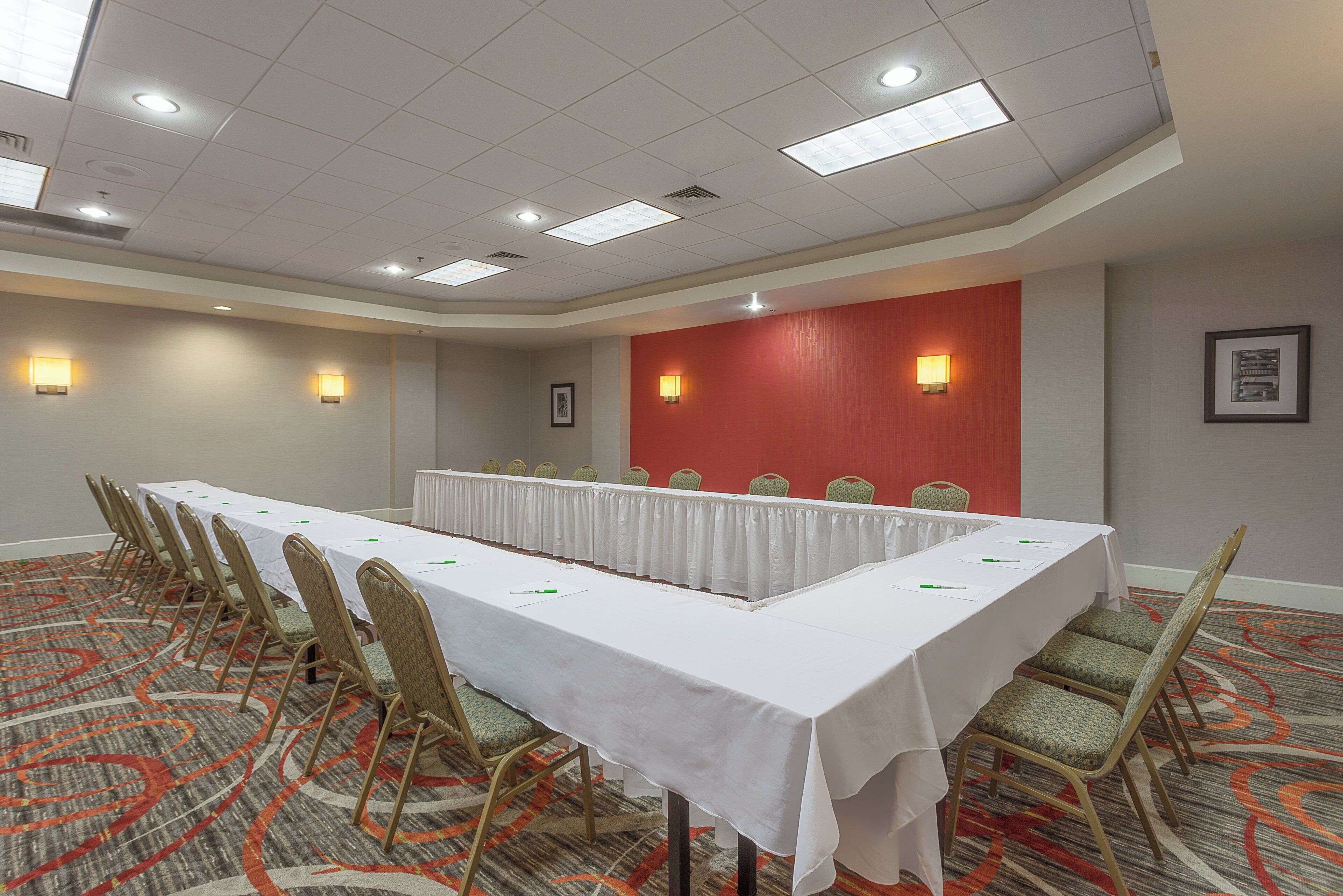 A conference room with a long table, chairs, and a red accent wall.