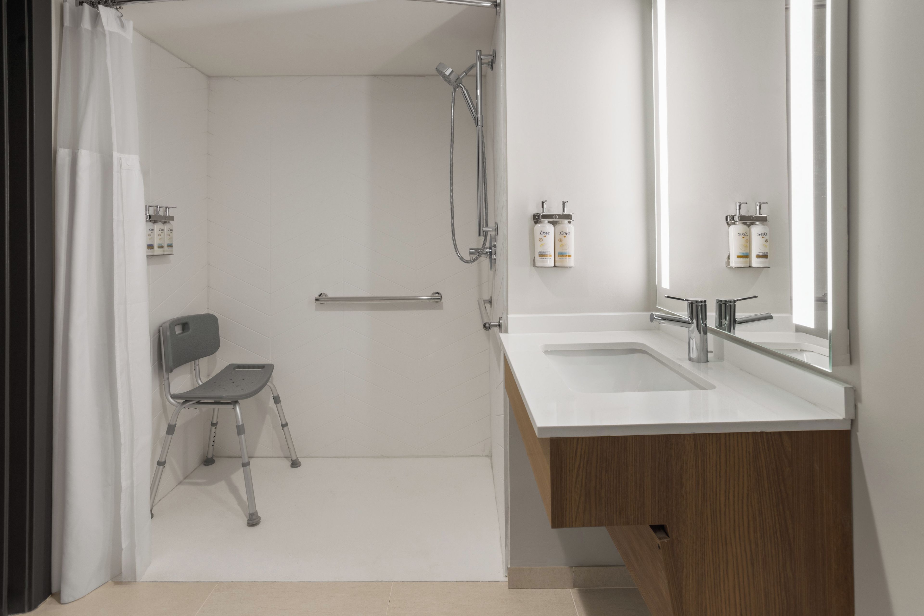 A modern bathroom with a shower, a toilet, a sink, and a mirror.