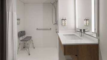 A modern bathroom with a shower, a toilet, a sink, and a mirror.