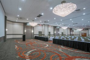 A conference room with a long table, multiple chairs, a podium, and a carpet with a circular pattern. - Holiday Inn Harrisburg - Hershey Area, I-81 by IHG (Grantville)