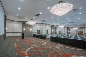 Un salón de conferencias con una larga mesa, varias sillas, un atril y una alfombra con un diseño circular.